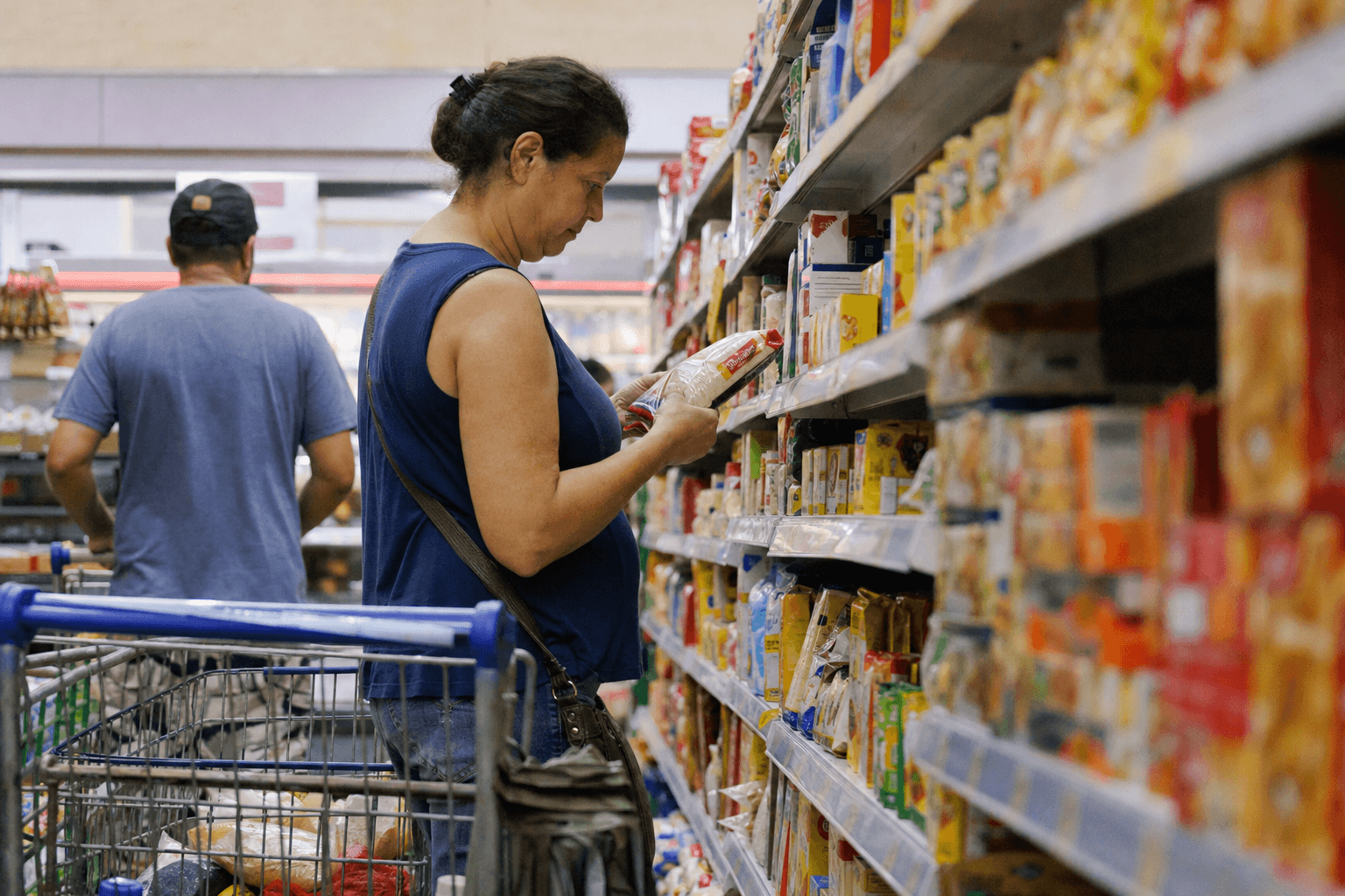Shopper comparing grocery prices in a Brazilian supermarket aisle