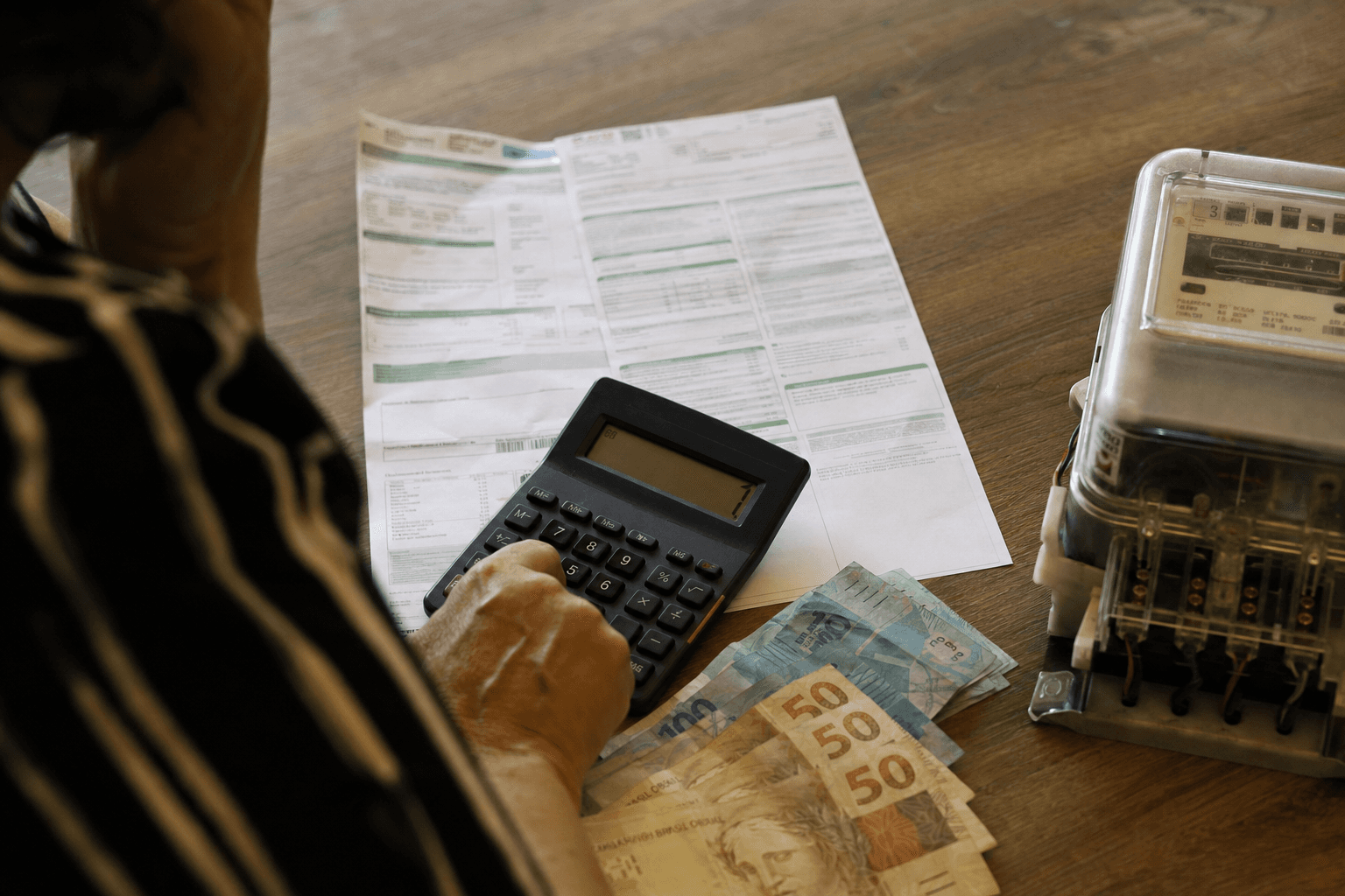 Electricity bill, calculator and Brazilian real notes on a table